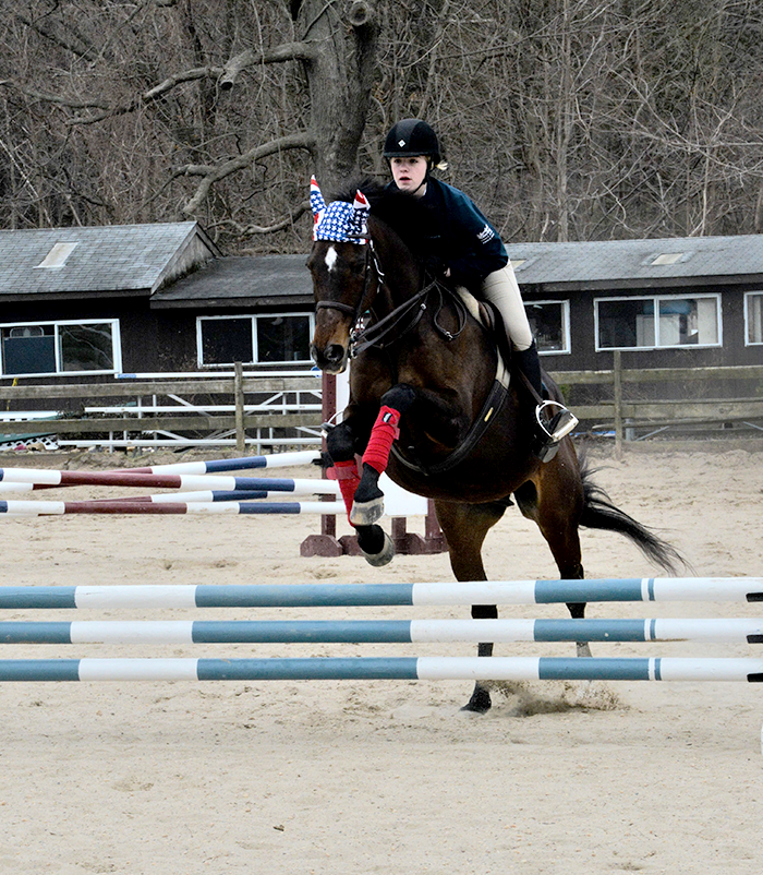 girl jumping over jump with horse
